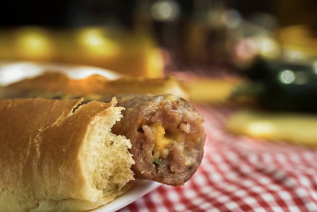 Cheddar jalapeño bratwurst in a bun showing melted cheese and pepper cross-section