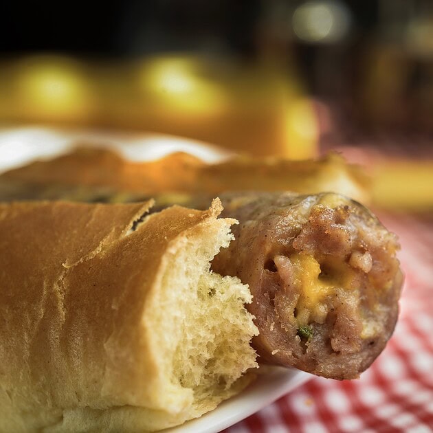 Cheddar jalapeño bratwurst in a bun showing melted cheese and pepper cross-section
