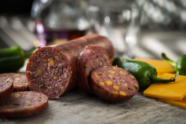 Cheddar jalapeño summer sausage log and slices with peppers and cheese
