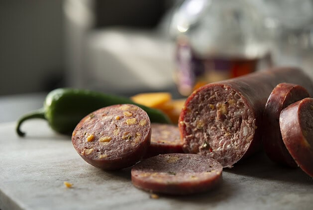 Sliced cheddar jalapeño summer sausage showing cheese and pepper pieces