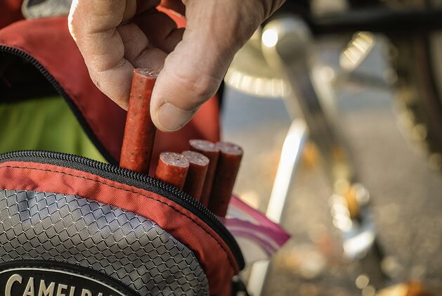 Snack sticks being pulled from a backpack, outdoor lifestyle shot