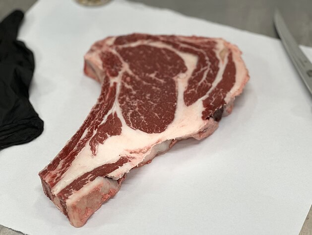 Raw bone-in ribeye cowboy steak on butcher paper
