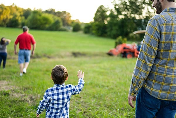 Family enjoying outdoor time in a lush green field with children and adults.