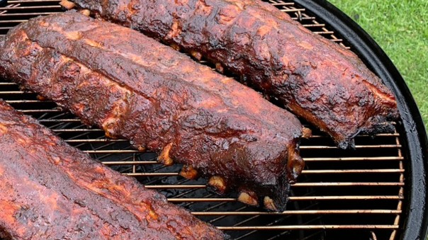 Four racks of smoked pork ribs on a grill